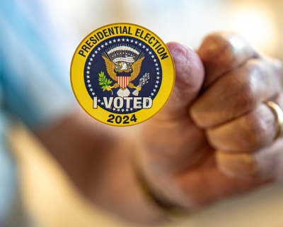 A man holds up a sticker that reads &quot;Presidential Election I Voted 2024&quot; on the first day of Virginia&#039;s in-person early voting at Long Bridge Park Aquatics and Fitness Center on September 20, 2024, in Arlington, Virginia.